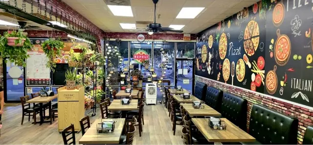 The Napoli dining room with booths, plants and the pizza mural wall